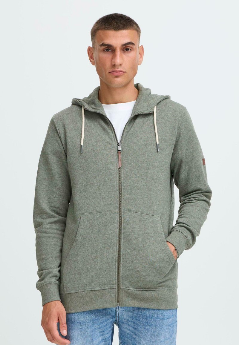 Grüne Zip-Hoodie aus weichem Stoff, mit einer Kapuze mit Kordelzug, Fronttaschen und einer dezenten melierten Textur.