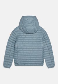 Giacca isolante azzurro chiaro con cappuccio, caratterizzata da una texture trapuntata orizzontale e polsini elasticizzati. Include un accento del logo arancione sulla manica.