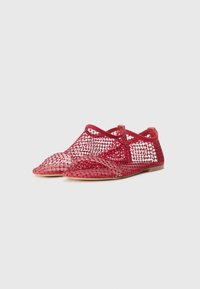 Red mesh shoes with a pointed toe and internal strap. Features a breathable net design and flat sole, providing a casual appearance.