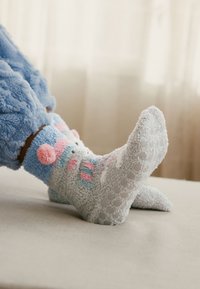 Szare, pluszowe skarpetki z pastelowymi różowymi i niebieskimi wzorami zwierząt. Posiadają podeszwy z antypoślizgowymi kropkami dla lepszej przyczepności. Miękka tekstura i długość do kostki.