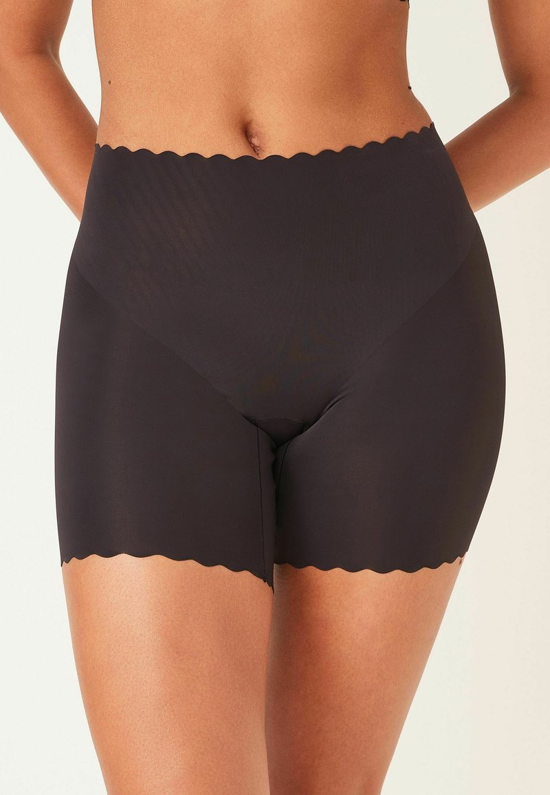 Hoogwaardige zwarte naadloze shapewear shorts met een golvende bovenrand, gemaakt van soepele, rekbare stof, ontworpen voor comfort en ondersteuning.