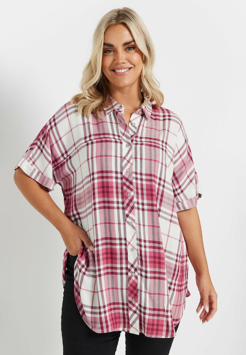 Camisa de cuadros en tonos rosa y blanco, con botones, mangas cortas, dobladillo redondeado y bolsillos laterales, que presenta una textura de tela suave y ligera.