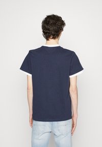 Marineblaue Baumwoll-T-Shirt mit kurzen Ärmeln, weißem Ausschnitt und geradem Saum. Glatte Textur, keine sichtbaren Muster oder Akzente.
