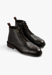 Botas negras de cuero hasta el tobillo con acabado texturizado, puntera redonda y cierre de cordones. Presentan detalles en marrón y un diseño de suela resistente.