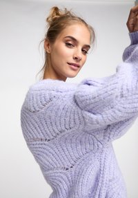 Hellblauer, gestrickter Pullover mit texturiertem Wellenmuster. Merkmale sind ein Übergröße-Schnitt, ein gemütlicher Look und leicht flauschiges Garn.