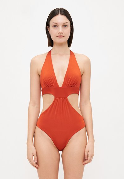 Maillot de bain une pièce rouge avec un décolleté en V profond, un design à encolure halter, des côtés découpés et une texture de tissu lisse.