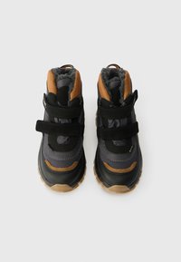 Fekete és szürke magasszárú cipők bézs kiemelésekkel; tépőzáras pántokkal, texturált szintetikus felsőrészel, szőrmes béléssel és gumitalppal rendelkeznek.