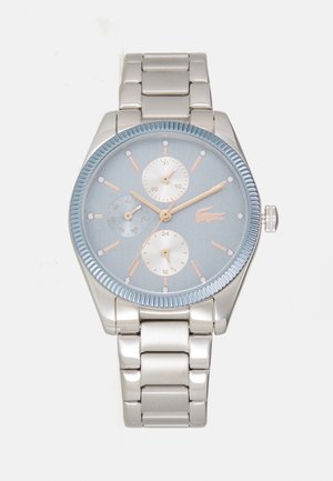 Reloj de acero inoxidable plateado con un dial azul claro, tres subdiales y acentos en oro rosa. Presenta un bisel texturizado y una pulsera de eslabones.