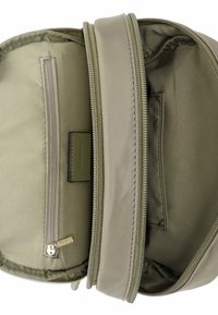 Kaki värvi kangast koti sisemus kahe kambri, ühe lukuga tasku ja ühe lameda taskuga, mis on varustatud siledalt vooderdatud ja õmblustetailidega.