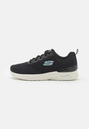 Baskets noires en mesh, avec une semelle blanche à éclaboussures, un logo bleu et des accents noirs contrastants sur le talon et la languette.