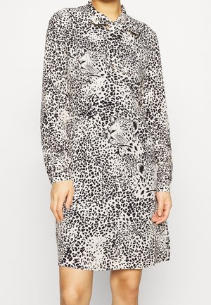 Langærmet, knælang kjole med sort-hvidt leopardmønster, der viser store leopardansigter foran.