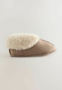 Miękki brązowy kapcie z pluszowym kremowym mankietem z polaru i widocznym przeszyciem wzdłuż podeszwy i boków.