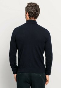 Dark navy knit sweater with a high collar and ribbed cuffs, featuring a smooth texture and a fitted design. Back view shown.