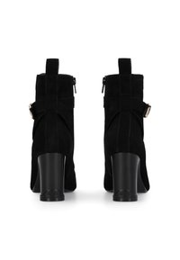 Botas de tobillo de ante negro con cierre de cremallera, con un tacón rectangular y una correa decorativa acentuada con un detalle de hardware en tono dorado.