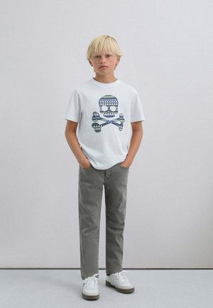 Tricou alb cu un grafic cu skull colorat, pantaloni gri și adidași albi cu accente bej. Design simplu, croi lejer și material din bumbac.