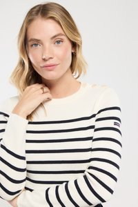 Suéter a rayas con franjas horizontales en azul marino y blanco, puños acanalados y botones decorativos en el hombro. Tejido suave.