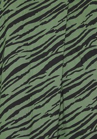 Tissu vert avec un motif de rayures de tigre noir, présentant une surface texturée et un design fluide, adapté pour les vêtements ou la décoration intérieure.