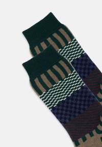 Calcetines con estampado en tonos verdes y marrones, con rayas, cuadros y un punto texturizado. Puños acanalados y diseños variados en cada calcetín.