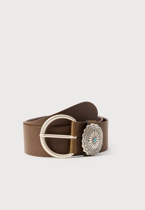 Cintura in pelle marrone con grande fibbia rotonda in argento e concho decorato in argento con motivo floreale e centro turchese, arrotolata su sfondo semplice.