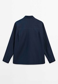 Chemise bleu marine à manches longues avec une coupe décontractée, col classique, empiècement droit et poignets à un bouton. Texture lisse et détails minimalistes.