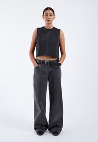 Black denim cropped tank top with raw edges, paired with high-waisted, wide-leg black denim jeans and a matching belt. Smooth texture.
