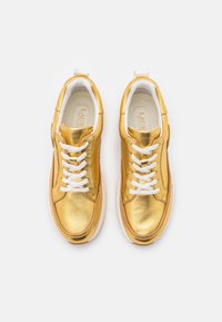 Guldmetalliska sneakers med vita snören, rund tå, vadderad krage och en dämpad sula. Slät textur med minimalistiska designelement.