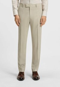 Ljus beige formella byxor med en slät textur, två sidofickor och rak passform. Bärs med bruna läderskor.