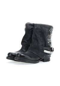 Botas de tobillo de cuero negro con una textura desgastada, que cuentan con una cremallera plateada, detalles con tachuelas y una correa decorativa con un detalle metálico.