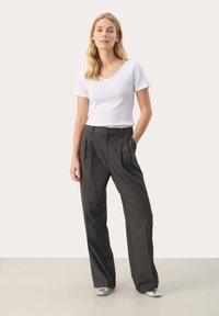 Witte T-shirt met korte mouwen en V-hals met een textuurpatroon, gecombineerd met hoogzwijnde, wijde charcoalkleurige broek en zilveren schoenen.