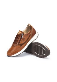 Sneakers in pelle marrone con design perforato, accenti beige e suola in gomma bianca. Presentano lacci e una zip laterale per una facile vestibilità.
