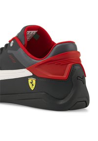 Czarno-czerwone sneakersy Puma z teksturowaną cholewką, z logo Ferrari, szczegółowym białym paskiem i wyściełanym kołnierzem.
