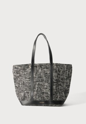 Sac fourre-tout tissé noir et blanc avec anses et bordure en cuir noir, forme rectangulaire, et petit nom de marque doré en bas au centre.