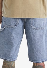 Vaaleansiniset denim-shortsit, joissa on kaksi takataskua ja yksi sivutasku. Ominaisuuksiin kuuluvat kontrastiväriset ompeleet ja rento istuvuus.