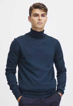 Donkerblauwe coltrui van een zachte gebreide stof, voorzien van lange mouwen en een aansluitende silhouette. Textuur met geribbelde kraag en manchetten.