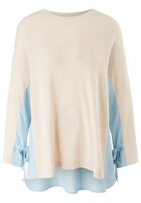 Pull en tricot beige avec des inserts en tissu bleu clair sous les manches et sur les côtés, doté de liens latéraux et d'un ourlet asymétrique.
