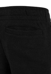 Primer plano de pantalones de tela de punto negra con una cintura elástica y un bolsillo trasero horizontal sin cierre.
