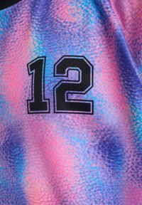 Lila och rosa tyg med mönster har ett svart "12" tryckt på sig. Designen har ett texturerat, gradientliknande utseende med livfulla färger.