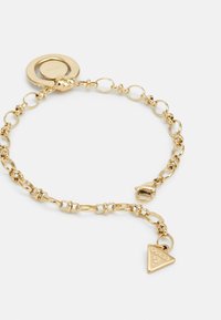 Pulsera de oro con cadenas ovaladas y redondas entrelazadas, un cierre circular y un charm triangular con logo grabado. Textura suave en toda la pulsera.