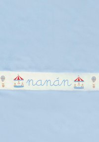 Un tessuto azzurro chiaro presenta una fascia bianca con elementi ricamati: la parola "nanán", un carosello e una mongolfiera in colori tenui.