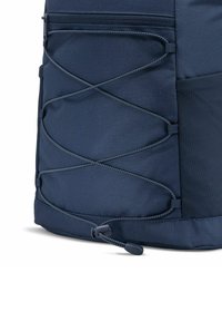 Zaino blu navy con tessuto testurizzato, dotato di un design con cordino elastico sul davanti, chiusura con corda regolabile e scomparti con zip.