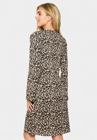 Leopardenmuster-Kleid mit langen Ärmeln, entspanntem Schnitt, knielangem Saum und glatter Stoffoberfläche. Individuelle Musterdetails überall.