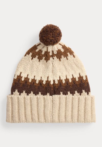 Strikket lue i kremfarge med brune geometriske mønstre og en brun dusk på toppen. Ribbestrikket kant nederst for ekstra tekstur.