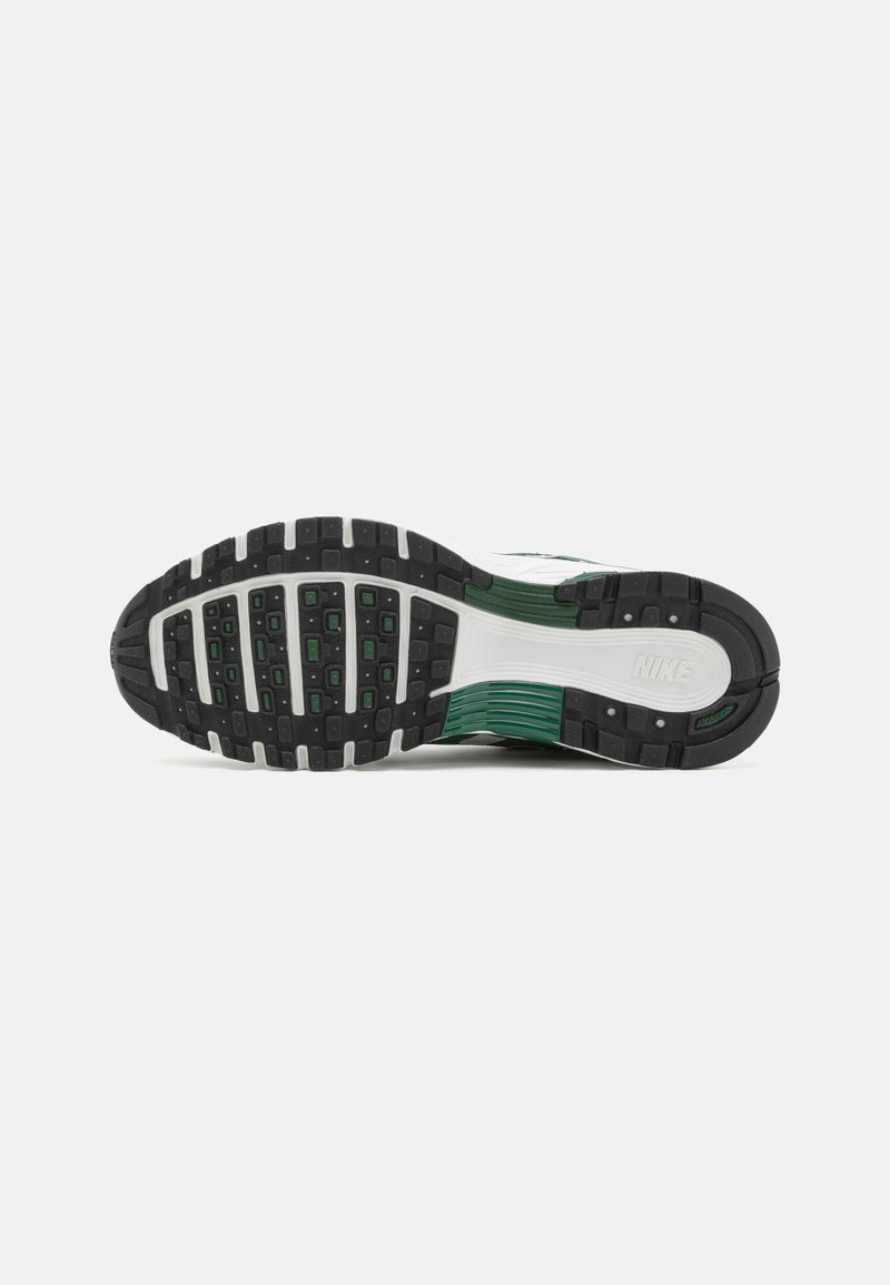 Semelle de sneaker Nike avec un caoutchouc noir, arborant un accent vert et des rainures texturées pour une adhérence et un soutien optimaux.