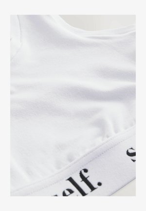 Prim-plan al unui articol de îmbrăcăminte din material alb, cu text negru parțial vizibil pe o margine sau un brâu.