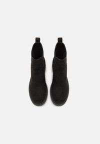 Botines de ante negro con un acabado suave, paneles laterales elásticos y tiradores en la parte posterior para poner y quitar fácilmente. Suela de goma plana.