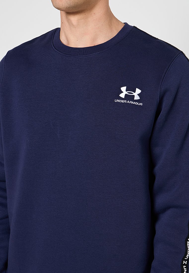 Granatowy sweter z bawełny z okrągłym dekoltem. Posiada białe logo Under Armour na klatce piersiowej oraz teksturowany materiał.