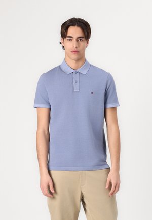 Polo shirt bleu clair à manches courtes, avec une patte de boutonnage à deux boutons et un petit logo sur la poitrine gauche. Fabriqué en coton lisse.