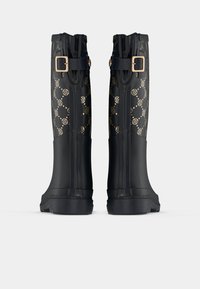 Fekete gumicsizmák, mintás szárakkal, arany díszítéssel, csat részlettel és masszív, mintás talppal.
