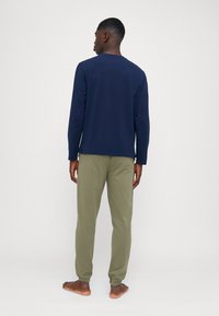 T-shirt à manches longues marine avec col rond associé à un pantalon de survêtement vert olive doté de poignets élastiques, fabriqué dans un tissu doux et respirant.