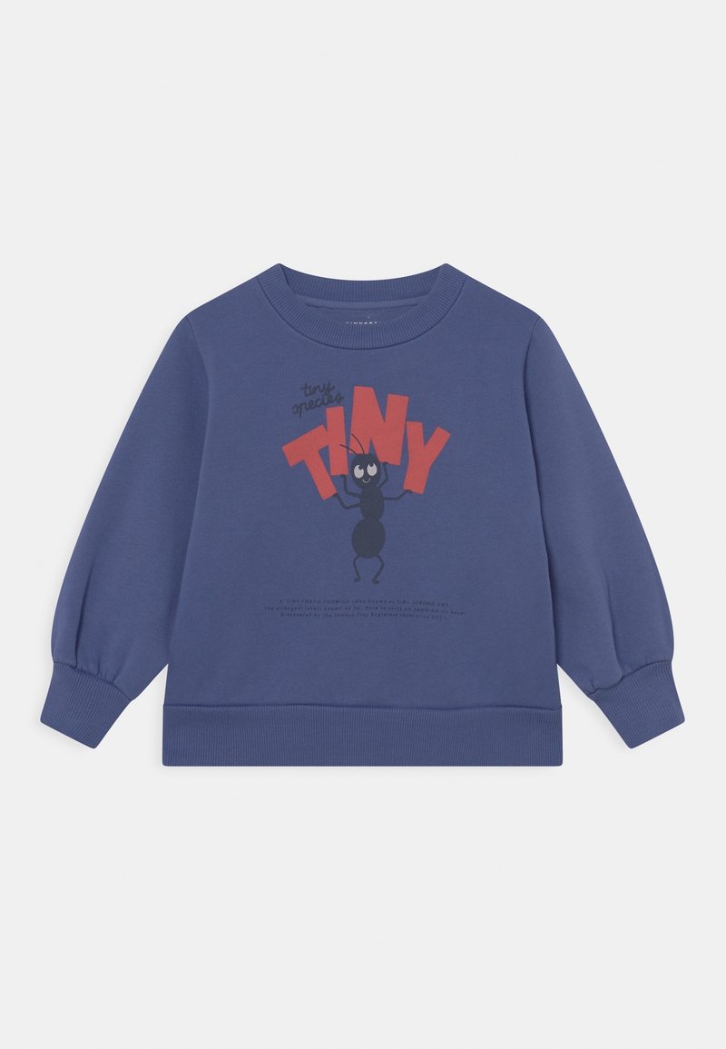 Sweat-shirt bleu à manches longues avec poignets et ourlet côtelés, présentant un dessin animé de fourmi tenant de grandes lettres rouges formant le mot "TINY" sur le devant.
